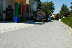  Die Schulstraße in Issigau im Jahre 2011, unmittelbar nach ihrer Sanierung. Hier haben die Kinder Vorrang: Der Pflasterbelag zeigt an, dass es sich hier um einen verkehrsberuhigten Bereich handelt. Der höhengleiche Gehweg wird sowohl farblich als auch dur 