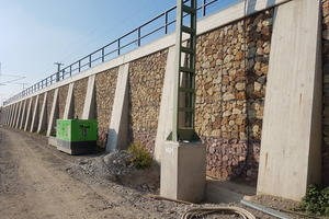  Sanierter Bahndamm mit vorgesetzter Gabionenverkleidung zwischen den Säulen des Stützbauwerks. 