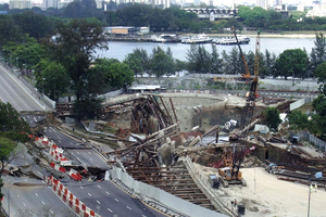  Tunnel-Baugrube in Singapur in offener Bauweise nach dem Einsturz: Im Hintergrund der Startschacht für den bergmännischen Vortrieb unter der Bucht. 