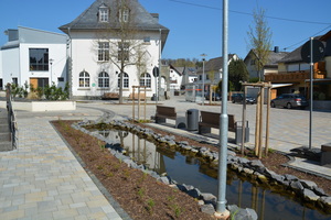  Zur Darstellung des Kerkerbaches wurde ein offener Bachlauf geschaffen, der sich in Muldenform über den Dorfplatz schlängelt und in einen kleinen Teich mündet. 