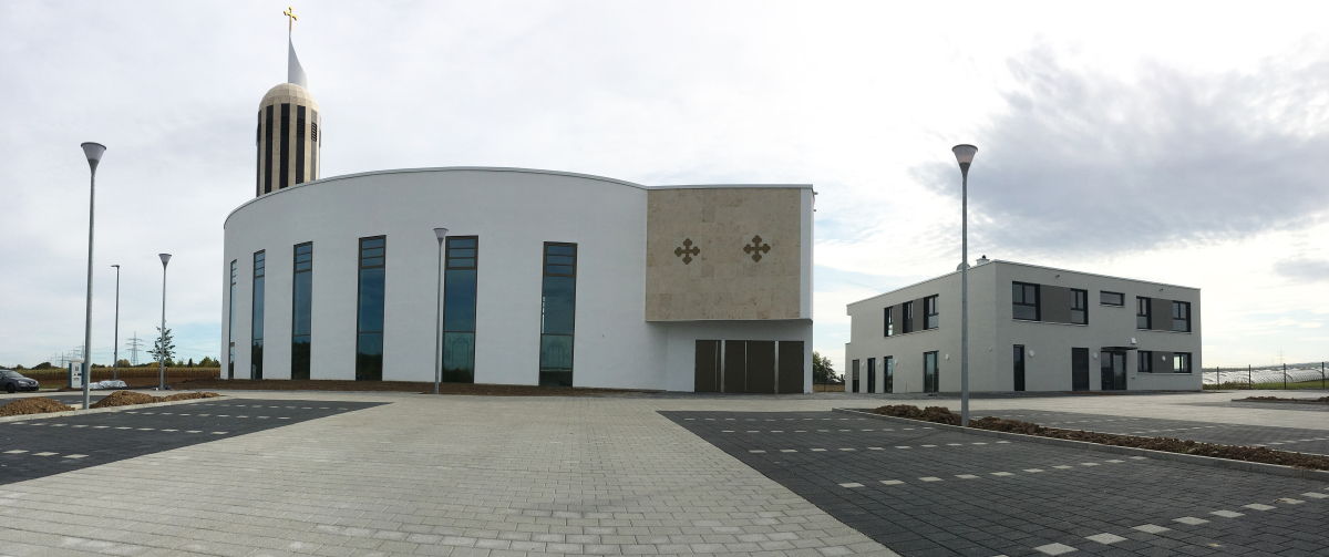 Der Parkplatz strukturiert das Gelände vor der Kirche.