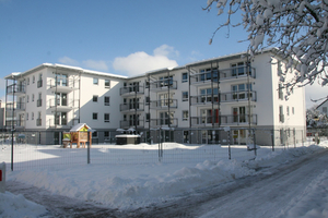  Im Erdgeschoss eines der drei neuen Gebäude ist ein Kindergarten untergebracht. Während im Winter eine Schneedecke die Außenanlagen bedeckt, bietet die großzügige Grünfläche im Sommer Platz zum Toben. 