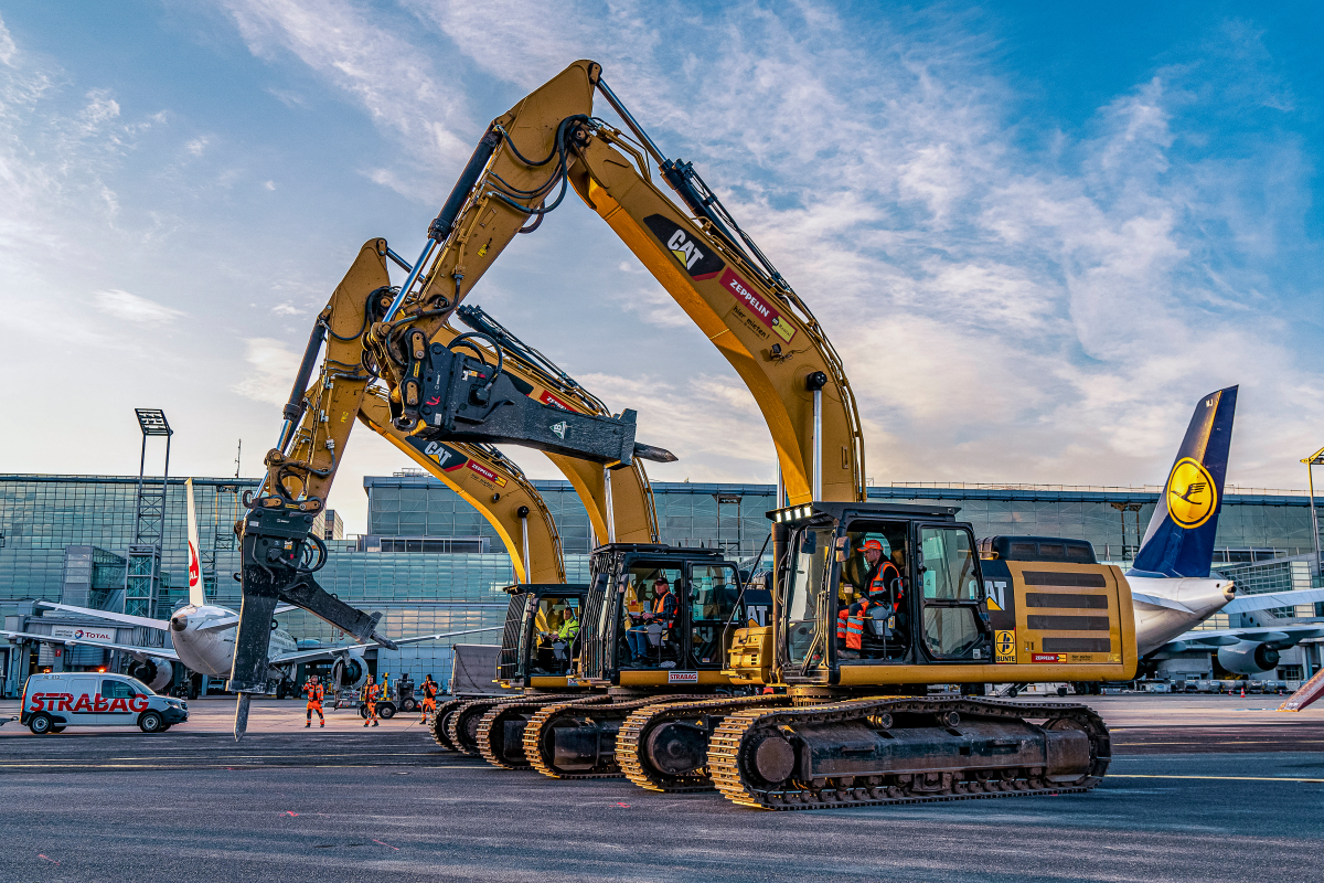 Vier Kettenbagger Cat 336 hämmern vor der Kulisse des Frankfurter Flughafens.