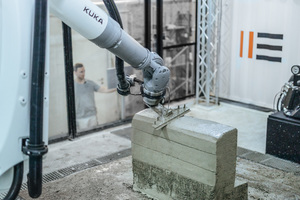  Schicht für Schicht wächst ein Gebilde mit Wellenstruktur, die von einem zweiten Roboter mit einem großen spachtelartigen Werkzeug glatt und in Form gestrichen wird. 