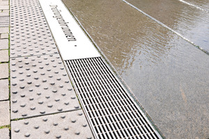  Im unteren Bereich bildet eine Stabile-Rinne mit Längsstabrosten den Abschluss. Auf eine mittig platzierte Edelstahlplatte wurde der Schriftzug „Dreiburgenbrunnen“ eingelasert. 