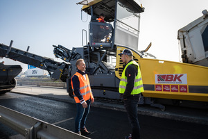  Gut zusammengearbeitet: Alexander Hirsch von der LeFa Finanz Leasing- und Finanzierungsagentur (links) neben Alexander Bermel von BK Asphaltmiet-service (rechts) auf einer Autobahnbaustelle in der Nähe von Krefeld. Im Hintergrund ein Beschicker von BK im Einsatz. 