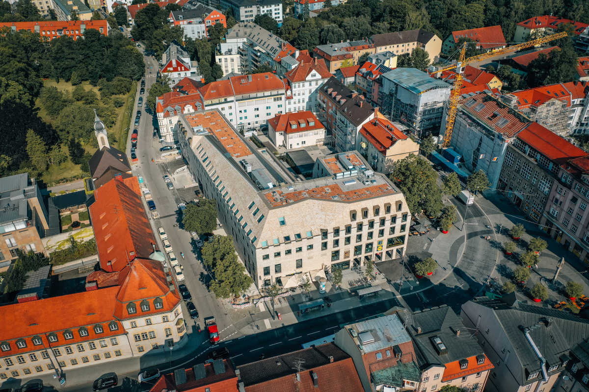 Das Hotel- und Geschäftsgebäude bildet mit seiner außergewöhnlichen Dachform und Fassadengestaltung einen markanten Stadtbaustein am Pasinger Marienplatz.