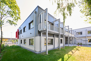 Auf der Südwestseite verbindet ein langgezogener Laubengang mit angesetzter Treppe die Freifläche mit dem Obergeschoss.