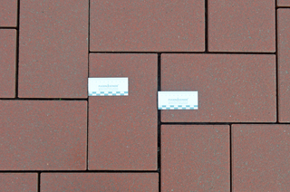 Abbildung 2: Eine ungebundene Betonsteinpflasterdecke mit geleerten Fugen und verschobenen Betonsteinen ist ersichtlich. Fugen haben sich verengt und auf der gegenüberliegenden Seite haben sie sich aufgeweitet.