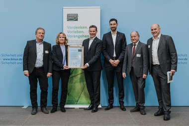 Bundesumweltministerin Steffi Lemke ?bergibt die Urkunde an Marc-Sven Mengis, Gesch?ftsf?hrer f?r die Bereiche Personal, Nachhaltigkeit und Geb?udemanagement (3.v.l.) und an Christian Ziegler, Bereichsleiter f?r Nachhaltigkeit, Umwelt und Energie (4.v.l.)