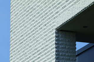 Weiße Kalksandstein-Verblender mit bossierter Oberfläche zieren die Fassade einer Wäscherei in Lohne.