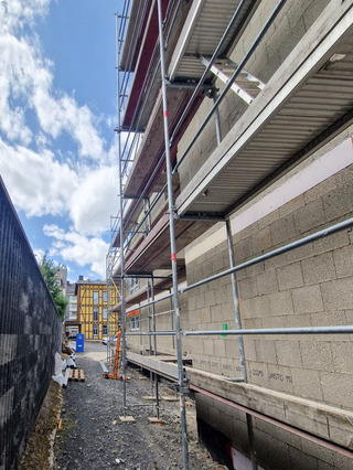 Das Wohngebäude liegt in der zweiten Reihe auf dem Grundstück hinter einem denkmalgeschützten Bauwerk.