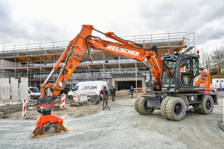 Bestückt mit einem Anbauverdichter verdichtet der Zaxis ZX155W-7 den Untergrund für zukünftige Parkplätze.