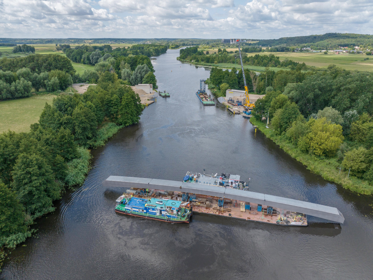 Die Ersatzwegebrücke wird zum Einbau auf einem Ponton von den Schubbooten in Position gebracht. Die Brücke kann dann mithilfe von Trägertürmen auf den Pontons angehoben und auf die Widerlager gesetzt werden.