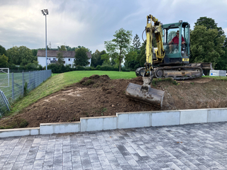 Verlegen der wasserdurchlässig befestigten, 650 m² großen Fläche vor dem Gebäude als Betonstein-Läuferverband, Fabrikat Kronimus Typ K4, Format 32/16 cm, 6 cm stark mit 5 mm Fugenbreite, Abflussbeiwert 0,3 ? 0,4.