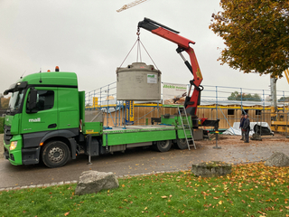 Lieferung des unterirdischen Regenspeichers PF 7600 aus Betonfertigteilen, mit integriertem Filterkorb im Zulauf und werkseitig vormontierten Wanddurchführungen für Zu- und Überlauf sowie einem Leerrohr als Verbindung zum Regencenter im Gebäude.