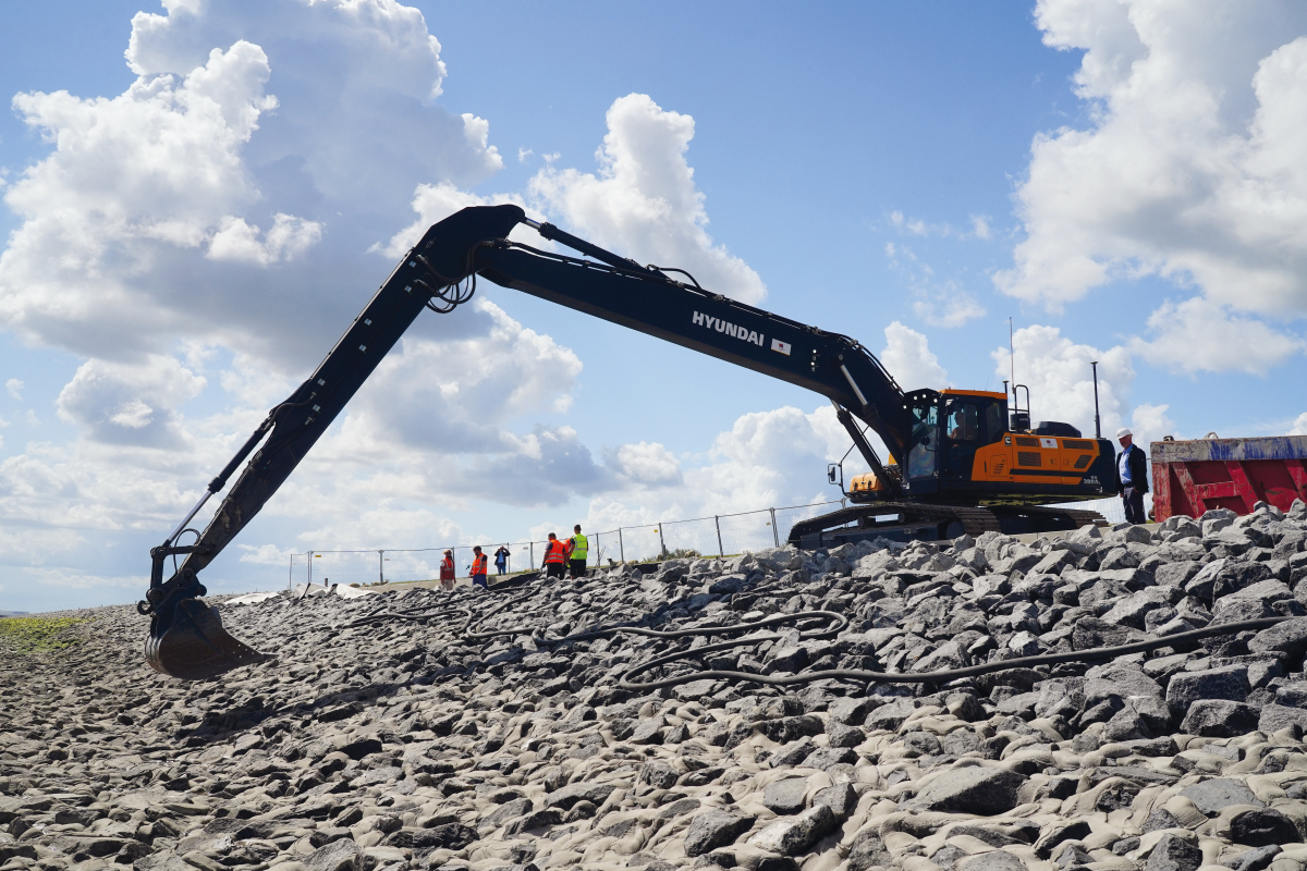 2.	Der mit 9,8-m-Monoblock plus 6,7-m-Stiel ausgerüstete seewasserfeste Großbagger hat Speziallackierung, mit Perlite gefüllte Ausleger/Stiel, vergrößertes Heckgewicht und eine GPS-Steuerung/Überwachung für eine Genauigkeit von ± 10 cm. Die Reichweite bet