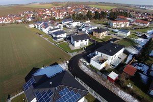  Die Wohnanlage am Ortsrand umfasst sowohl dreigeschossige Mehrfamilienhäuser als auch Ein- und Zweifamilienhäuser – jeweils ausgestattet mit Solarpanelen auf dem Dach.  