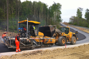  Insgesamt 70 m Höhenunterschied überwinden die Fahrer auf der kurvenreichen Rundstrecke. An einigen besonders steilen Passagen belieferten Radlader die Asphaltfertiger mit Heißmischgut. 