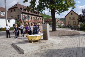  Der umgestaltete Place de Vouvrey mit Pflastersteinen aus beigefarbenen belgrano Granit präsentiert sich als schöne neue Mitte von Randersacker. Ein echter Hingucker ist der neue Brunnen „Balthasars Badewanne“, den der Künstler Matthias Braun entwarf.  