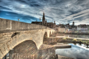  v.l.n.r.: In der Nähe des berühmten Regensburger Doms steht das zweite Wahrzeichen der Stadt: Die Steinerne Brücke – erbaut zwischen 1135 und 1146 – verbindet die Altstadt über die Donau mit dem Stadtteil Stadtamhof.Seit 2011 wird die Steinerne Brücke nun in vier Bauabschnitten instand gesetzt. Die Fertigstellung ist bis 2017 geplant.Man entschied sich für den Einbau einer hochelastischen Spritzabdichtung aus einem 2-Komponenten-Harz auf Polyurethan-Basis. Diese Abdichtung wird mit Hochdruckspritzmaschinen auf eine zuvor sandgestrahlte Trägerschicht aus Gussasphalt aufgebracht. 