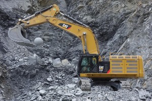  Die Baumaschine hantiert mit einer Knäpperkugel, die zwischen zwei Baggerzähnen eingeklemmt wird. Sie dient zum Zertrümmern von Gesteinsbrocken. 