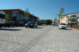  Anthrazitfarbene Bänderungen teilen den Platz in unterschiedliche Funktionsbereiche ein. Links die neue Turnhalle, rechts das Seniorenzentrum Foto: Betonwerk Pfenning GmbH 