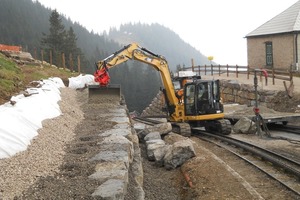  Oberhalb der Böschungsmauer baut der Bagger mit einem Wimmer-Tiltrotator und seitlich geschwenkter Räumschaufel schnell und präzise Schotter als Hinterfüllung einFoto: Wimmer 