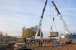  Mit Hilfe von zwei Autokränen wird das erste Teil des Schachtbauwerkes in die Baugrube abgelassen 