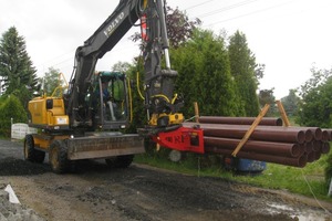  Das können weder Teleskopstapler noch Radlader: Mit engcon-Tiltrotator am Ausleger und seitlich geschwenktem Gabelträger bringt der Bagger lange, für den Weg eigentlich zu breite Rohre zum EinbauortFoto: engcon 