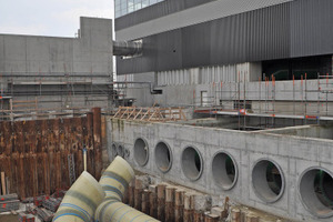  Vor der mächtigen Fassade des Kraftwerks-Kesselhauses wurden im Frühjahr 2011 zuerst die Rohre DN 2000 des Kondensatrücklauf-Systems installiert; die Vorlaufrohre gingen später über diese hinweg 