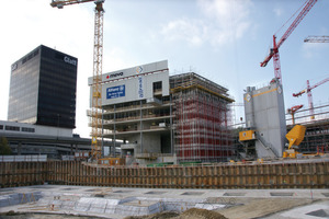  Kräne und rege Bautätigkeit überall auf dem Richti-Areal. Am Bürohochhaus sind die oberen Etagen der Seitenfassade komplett durch das MGS abgesichert. An der Stirnfassade wachsen die MEP-Traggerüste zum Abstützen einer auskragenden Decke mit dem Baufortschritt in die Höhe. Hinter dem Hochhaus ist das 6-stöckige Bürogebäude im Bau, in das ebenfalls die Allianz Suisse einziehen wird 