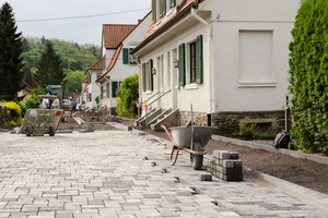  Eine Straße in der Kolonie wird komplett gepflastert. Die Parkbuchten heben sich durch einen etwas dunkleren Farbton ab 