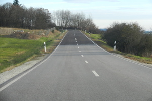  Zwei Jahre nach dem Einbau ist die Aufhellung auf dieser Landstraße deutlich sichtbar. Der Abrieb des Bitumens wird dabei vor allem durch Umwelteinflüsse und weniger durch die Verkehrsbelastung hervorgerufen und führt zu einer gleichmäßigen Oberflächenbeschaffenheit. 